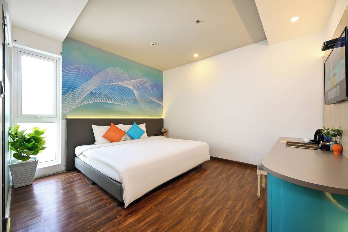 A modern hotel room with a large bed, a desk, and a wall-mounted TV.