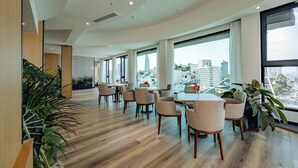 A modern hotel lobby with wooden flooring, large windows offering city views, and several seating areas. - Cicilia Saigon Center (Ho Chi Minh City)