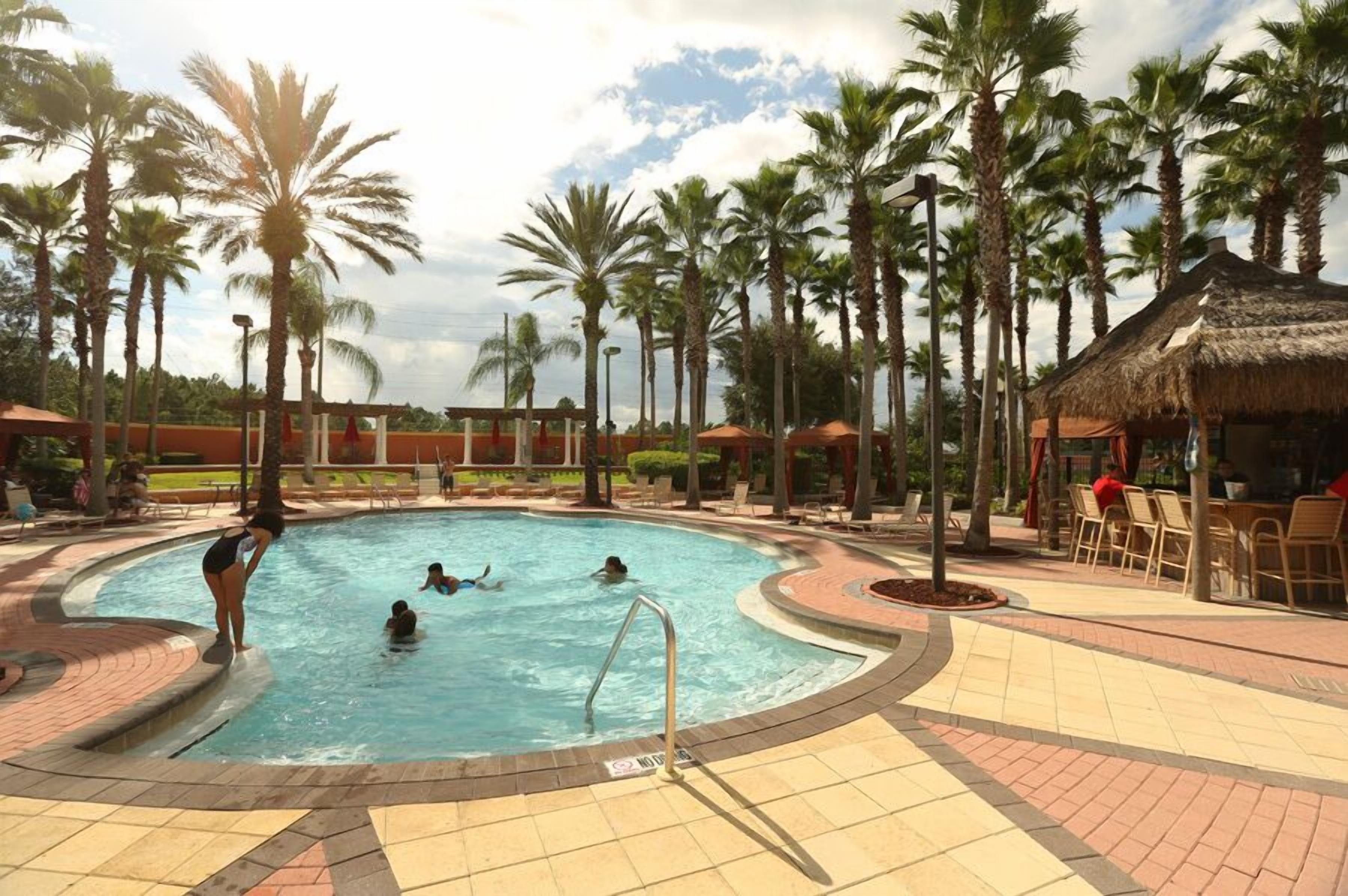 A swimming pool surrounded by palm trees and outdoor seating areas.
