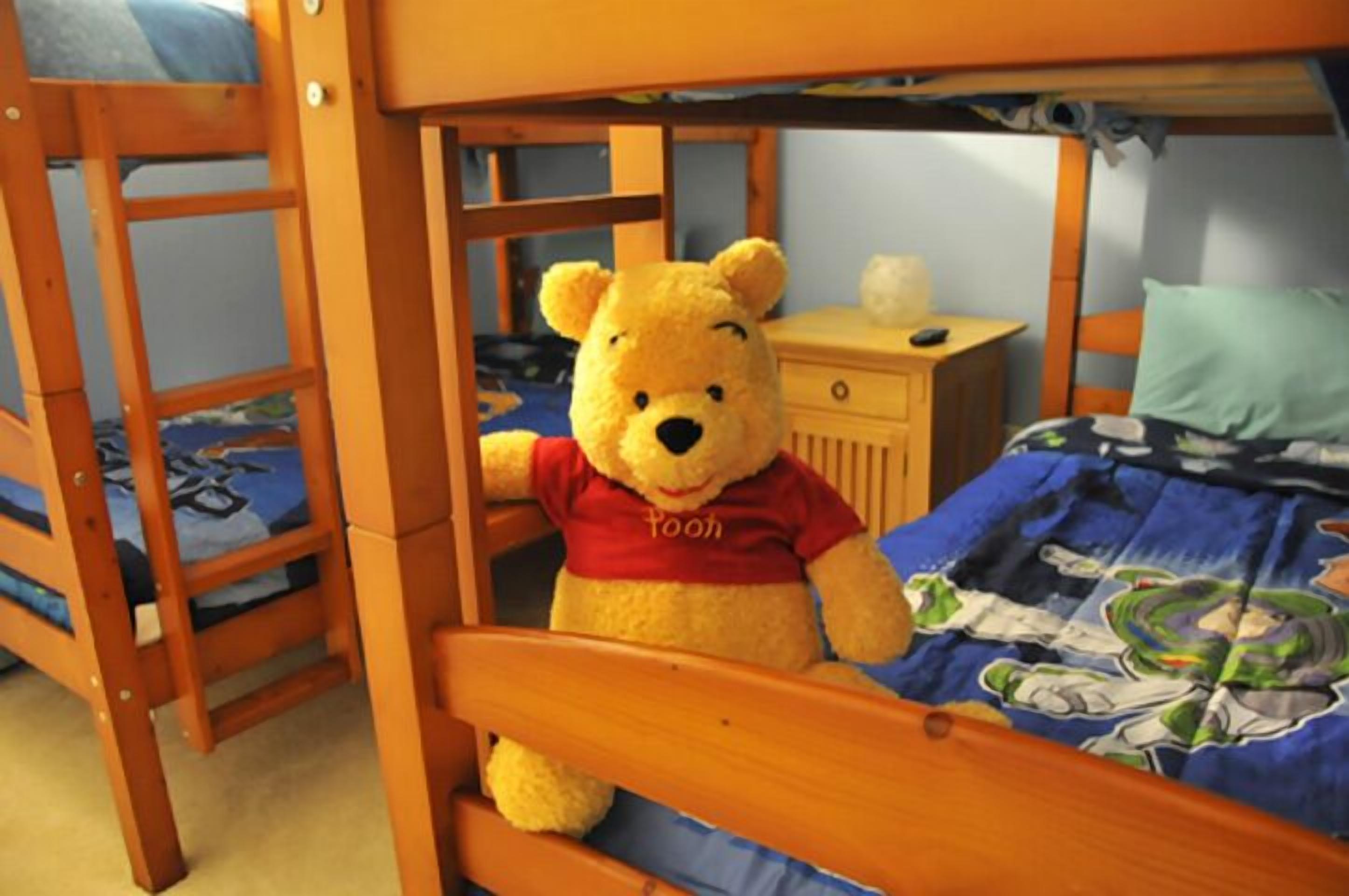 A bunk bed with a stuffed Winnie the Pooh toy on the lower bunk.