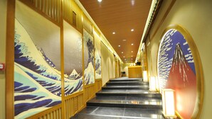 Un pasillo con arte tradicional japonés en las paredes, una escalera y un mostrador de recepción.