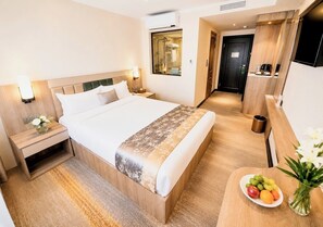 A hotel room with a bed, bedside table, nightstand, and a small table with fruit and flowers. - Flower Hotel Ulaanbaatar (Ulaanbaatar)