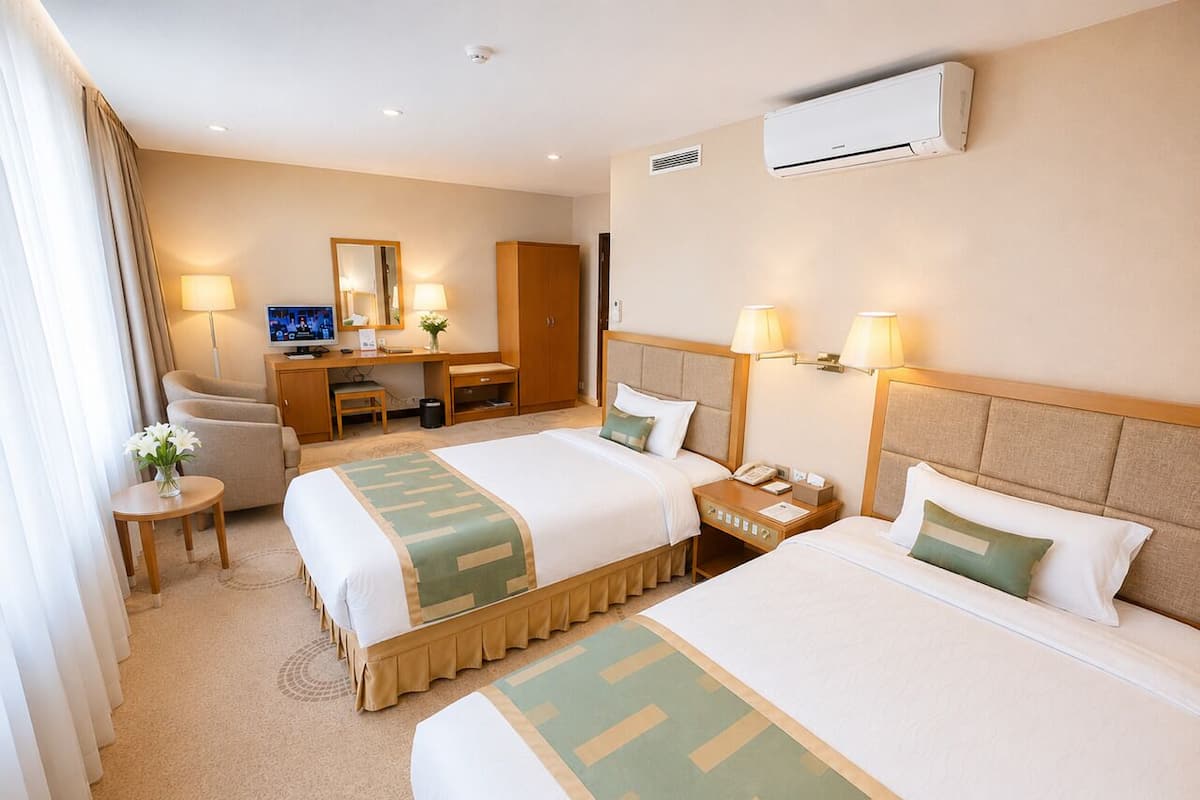 A hotel room with two beds, a desk, a chair, a TV, and a mirror.