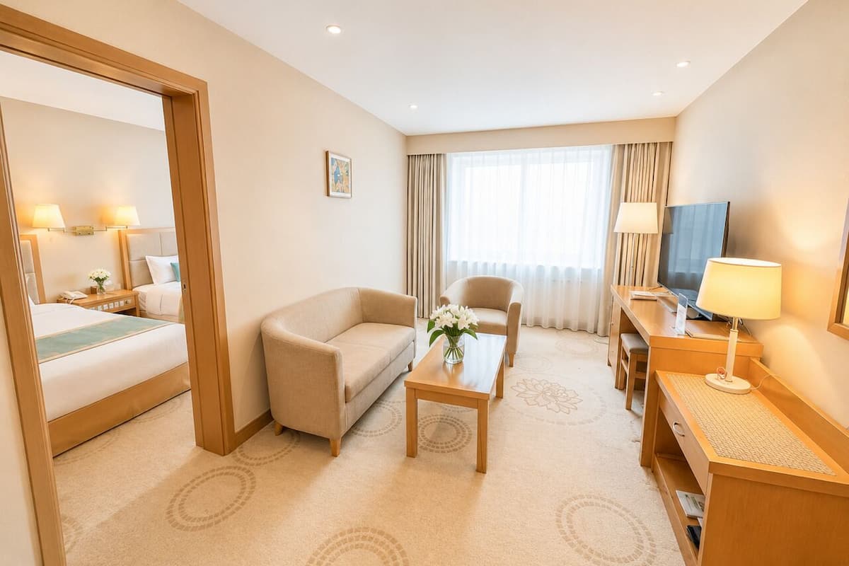 A hotel room with a bed, two sofas, a coffee table, a TV, and a desk with a lamp.