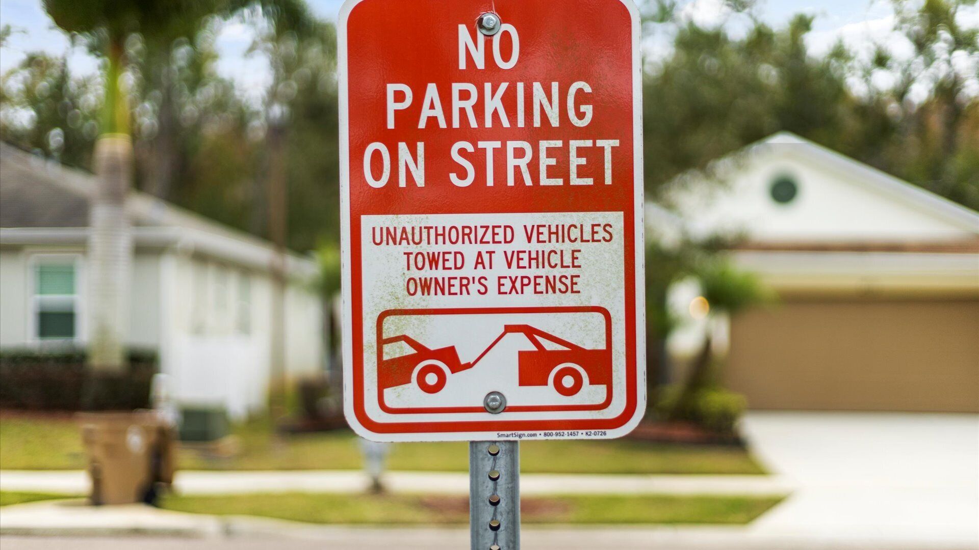 A 'No Parking on Street' sign with a warning that unauthorized vehicles will be towed at the owner's expense.