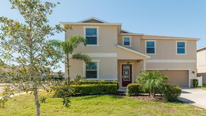 A two-story residential building with a front entrance, a garage, and a well-maintained lawn. - Shv1189ha - 7 Bedroom Villa In Crystal Cove, Sleeps Up To 16, Just 6 Miles To Disney (Kissimmee)