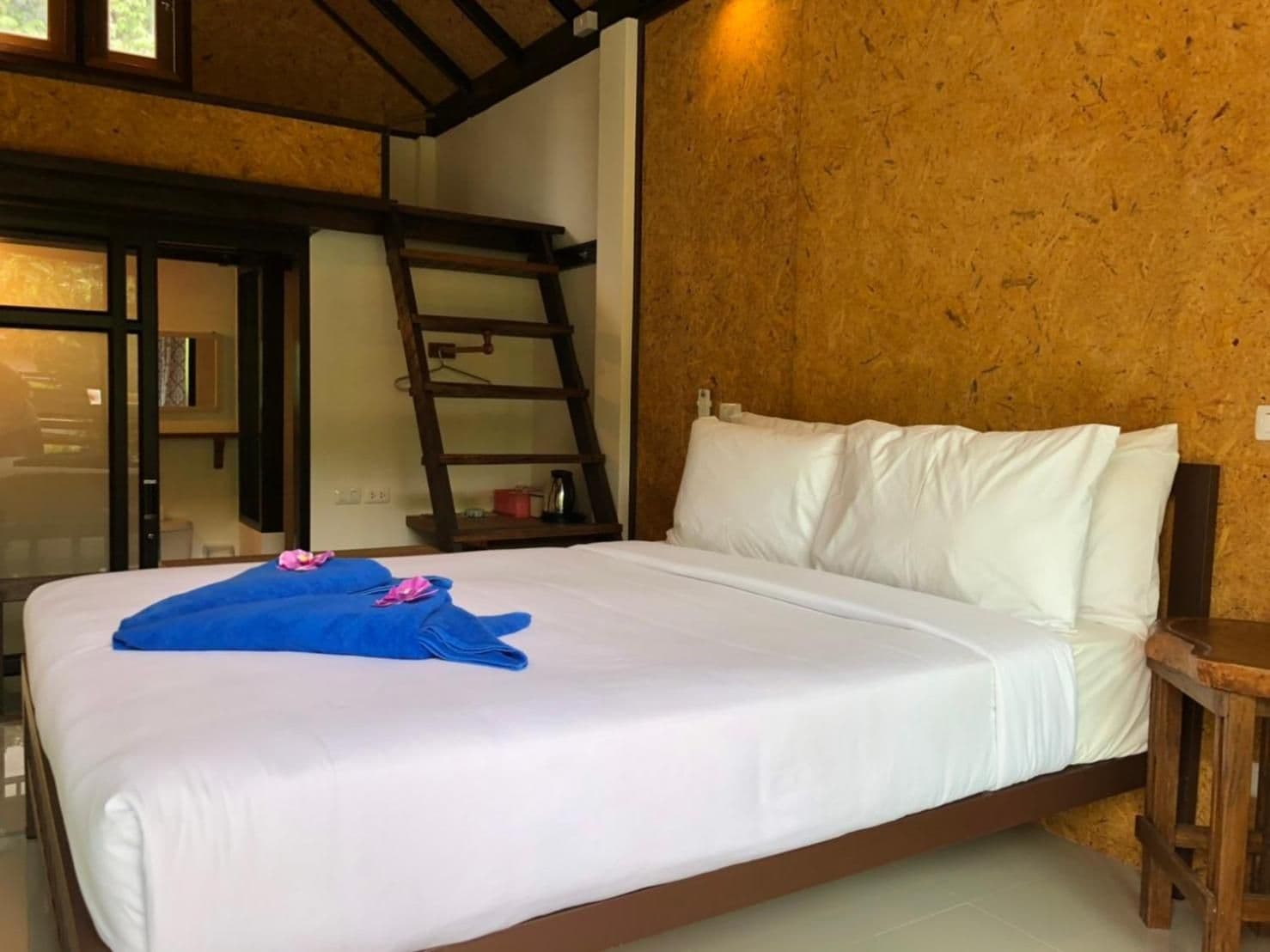 A bedroom with a bed, white pillows, a wooden ladder, and a small table.