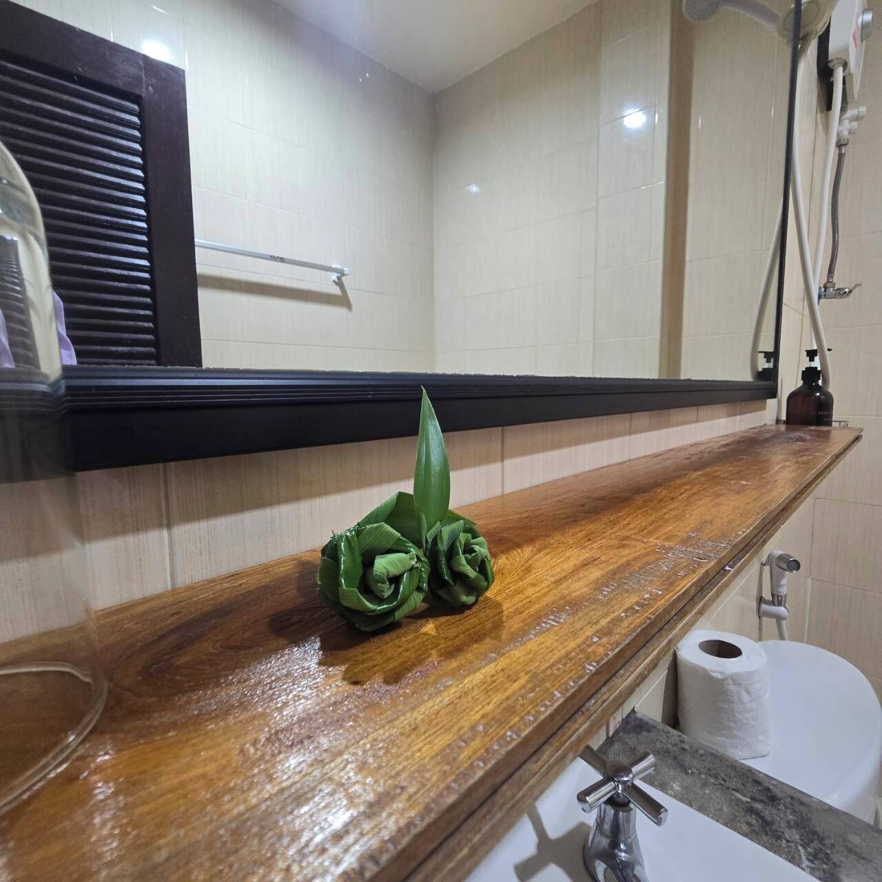A bathroom with a wooden vanity, a toilet, and a shower area.
