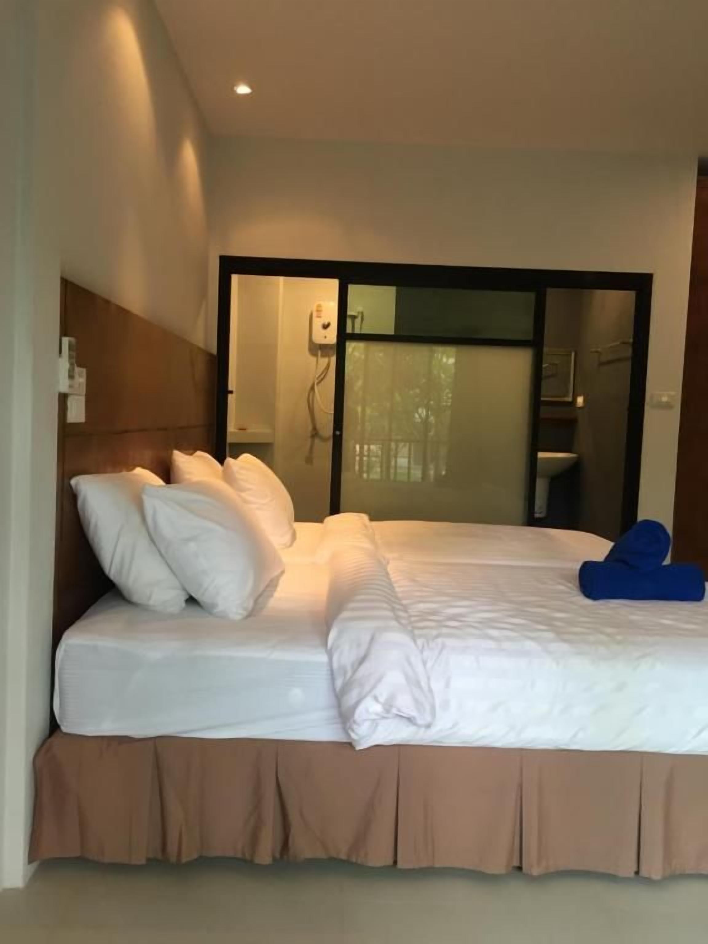Une chambre d’hôtel comprenant un lit, une tête de lit, une porte coulissante et un luminaire fixé au mur.