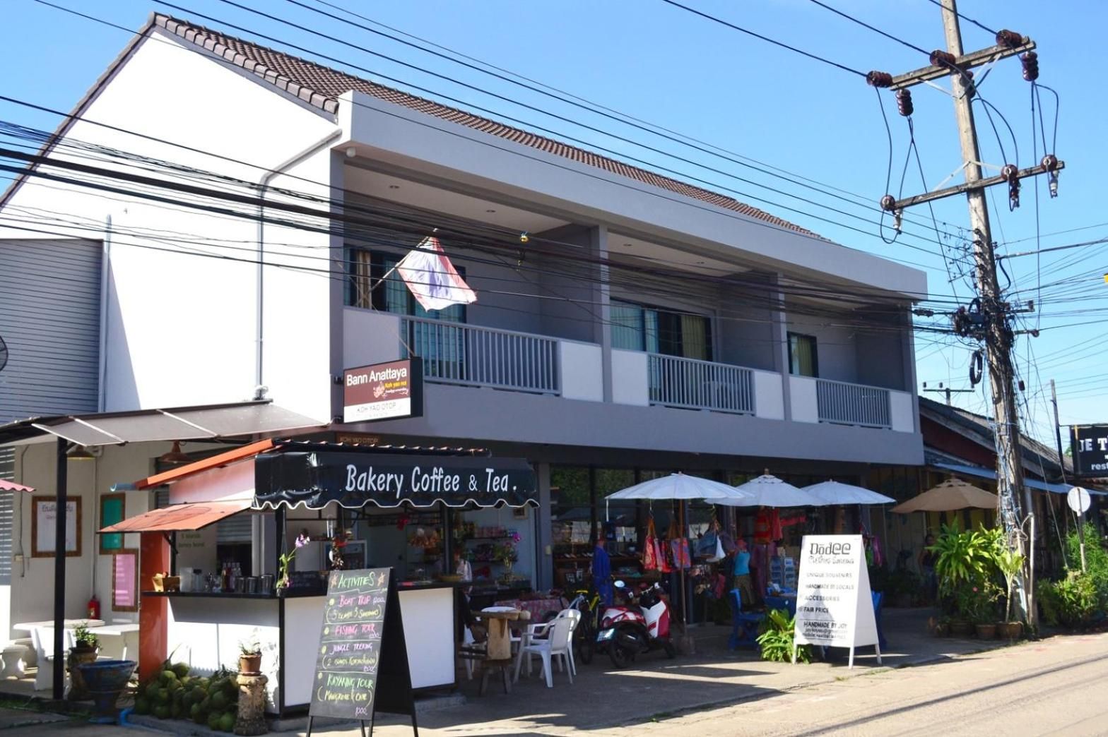 Un edificio de dos pisos con una panadería, cafetería y tienda de té en la planta baja.