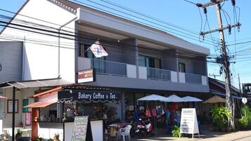 Un edificio de dos pisos con una panadería, cafetería y tienda de té en la planta baja.
