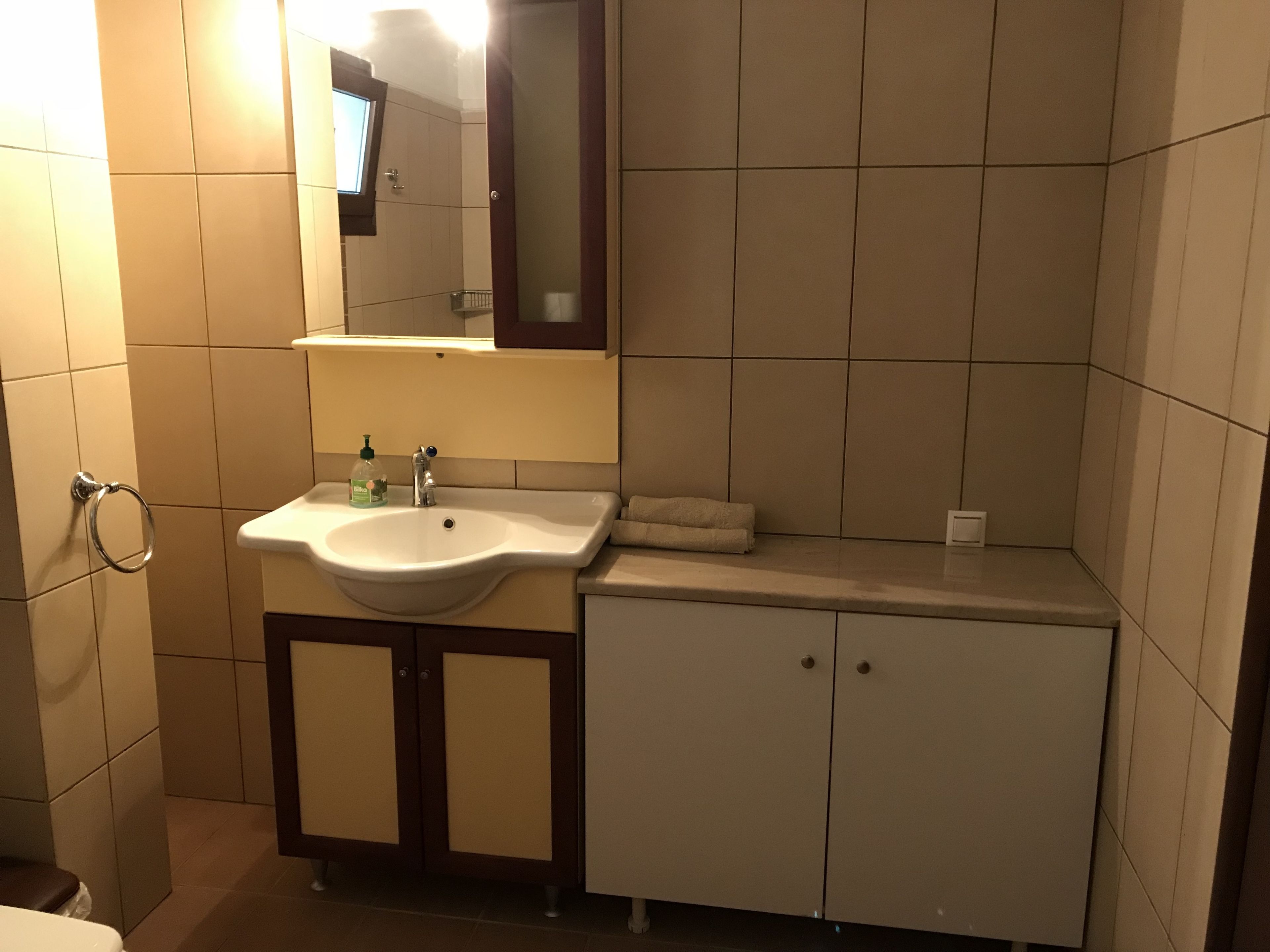 Ein Badezimmer mit Waschbecken, Spiegel und Schränken.