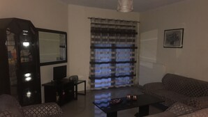 Un salón con un conjunto de sofá, una mesa de centro, un televisor y un espejo.
