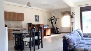 Un espacio habitable compacto con comedor, kitchenette, equipo de ejercicio y sofá.