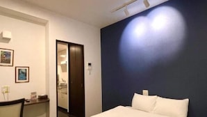 Ein Hotelzimmer mit Bett, Schreibtisch und Stuhl. Eine Tür führt zu einem Badezimmer.