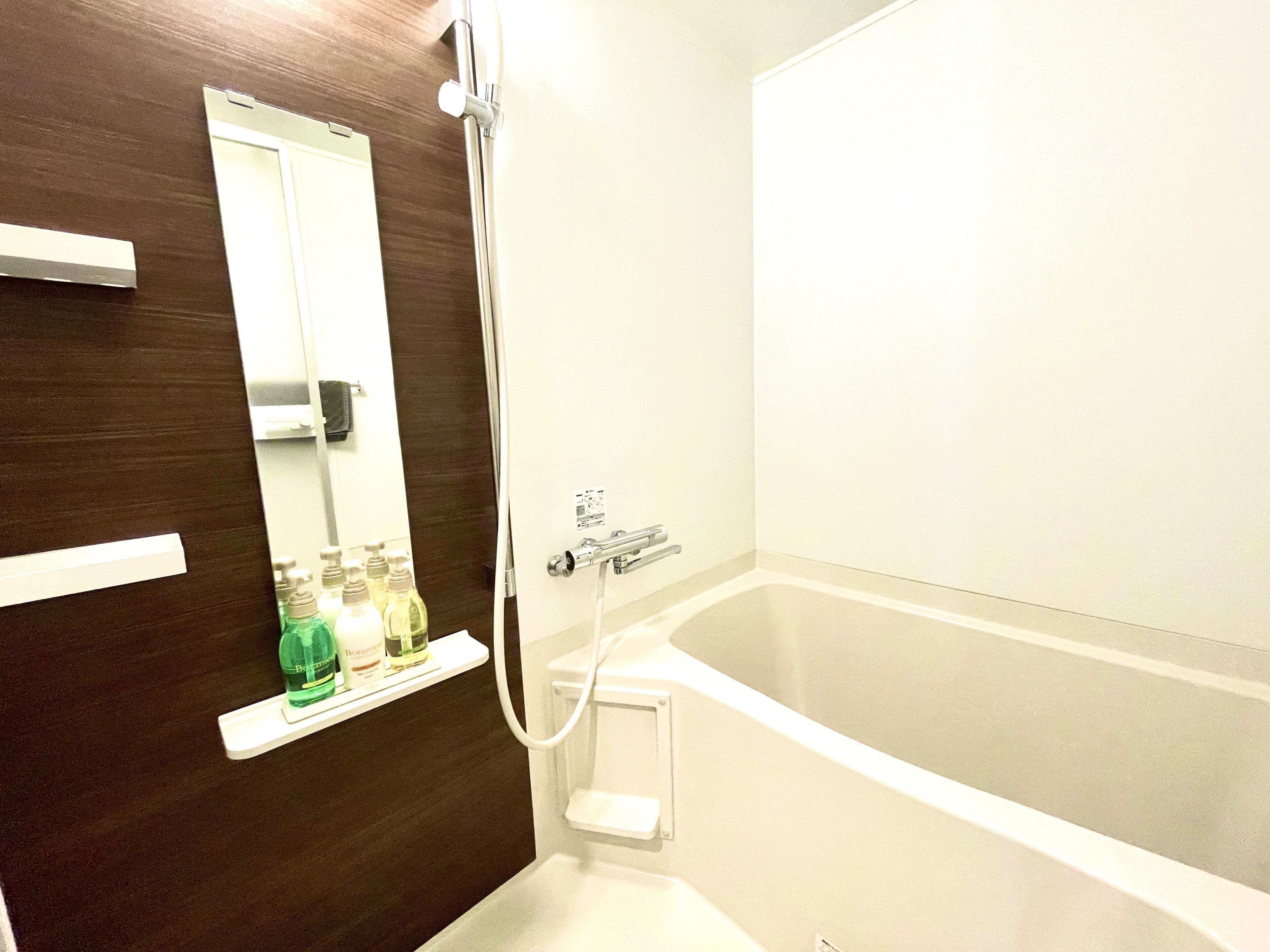 Un baño con bañera, ducha y un espejo colocado en una puerta de madera.
