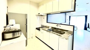 Eine moderne Küche mit weißen Schränken, einem Edelstahlkühlschrank, einem eingebauten Backofen und einem großen Fenster für natürliches Licht.