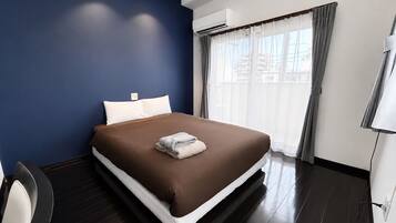 Una habitación de hotel con una cama, un escritorio y una ventana con cortinas.