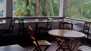 An outdoor seating area with tables and chairs, overlooking a lush green landscape. - La Cima Kandy (Kandy)