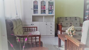 A living room with a sofa, a wooden coffee table, a cabinet with books, and a floral arrangement. - La Cima Kandy (Kandy)