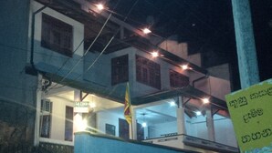 A building with multiple floors, a sign indicating 'LA CIMA ROOM' on the ground floor, and a flagpole with a flag. - La Cima Kandy (Kandy)