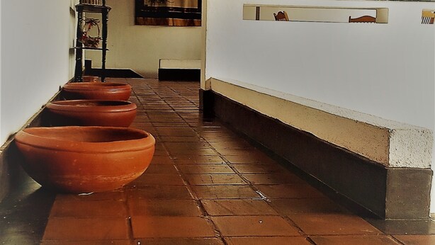 A corridor with terracotta pots lined up on the left, a ceiling fan, and a window with curtains. - La Cima Kandy (Kandy)