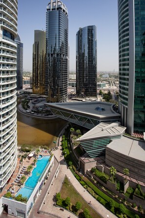 A high-rise hotel with a swimming pool, a bridge, and a river.