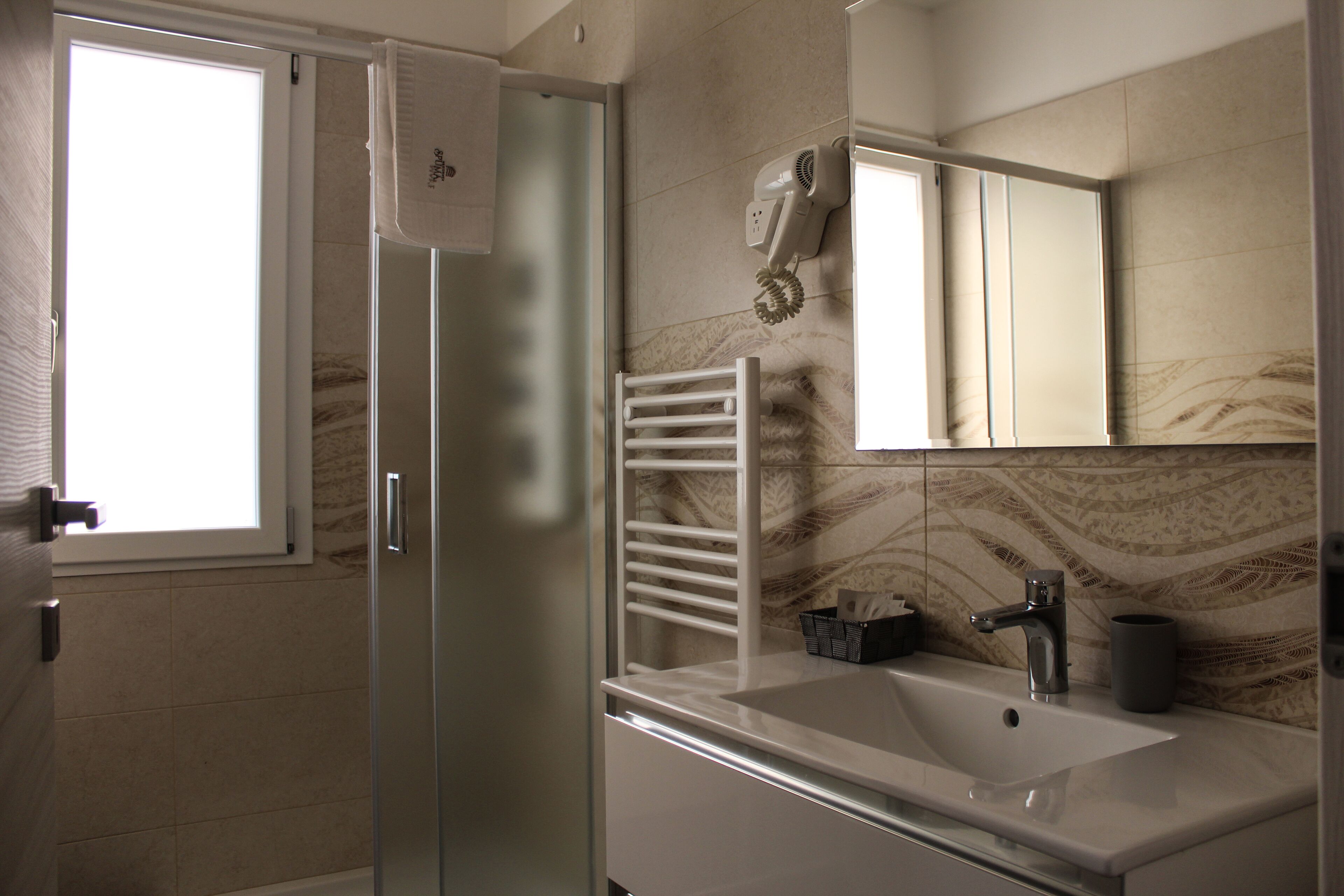 Ein Badezimmer mit Glasduschtür, Waschbecken, Handtuchhalter und Spiegel.