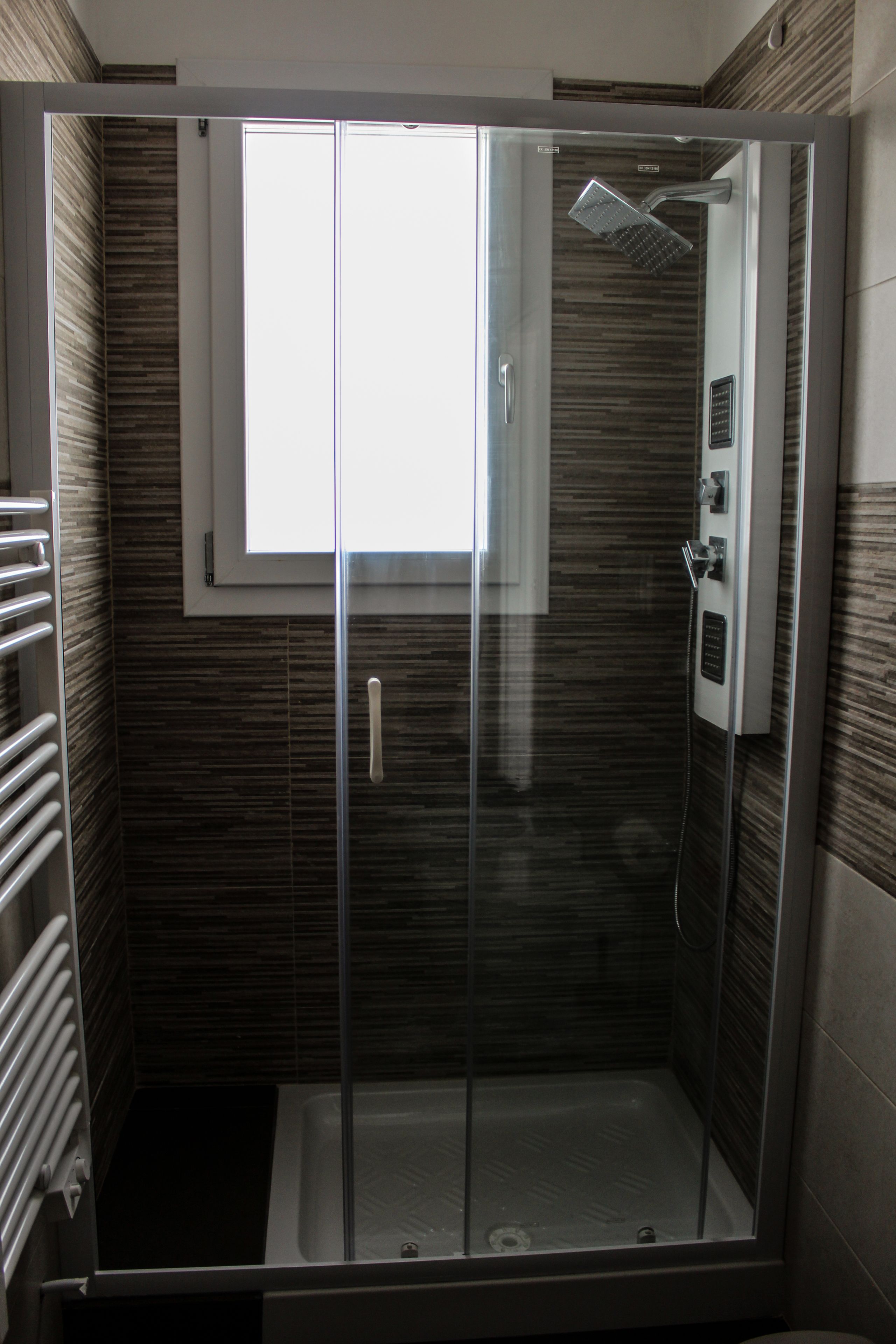 A modern shower enclosure with a glass door, a built-in window, and a showerhead.
