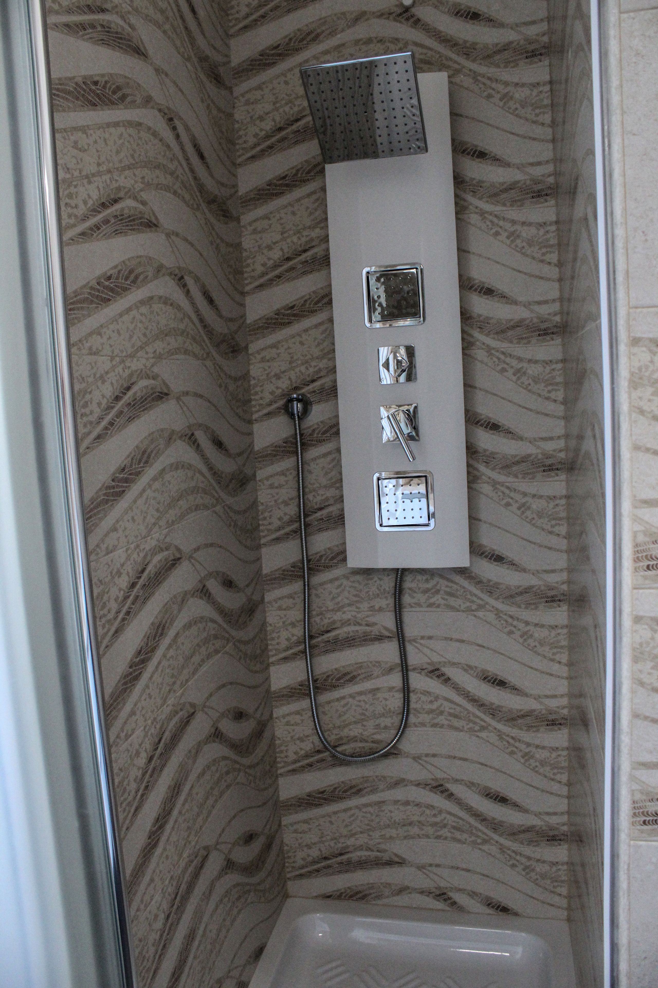 Une douche équipée d'un panneau de commande et d'un pommeau de douche à main.