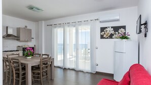 Una cocina moderna con una mesa de comedor y sillas, un sofá rojo y un balcón con vistas.