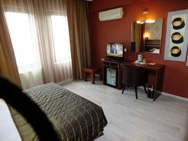 Une chambre d’hôtel équipée d’un lit, d’un bureau, d’une télévision et d’un réfrigérateur.