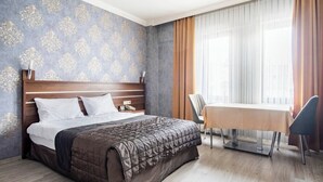 Una habitación de hotel con una cama, un escritorio y una silla.