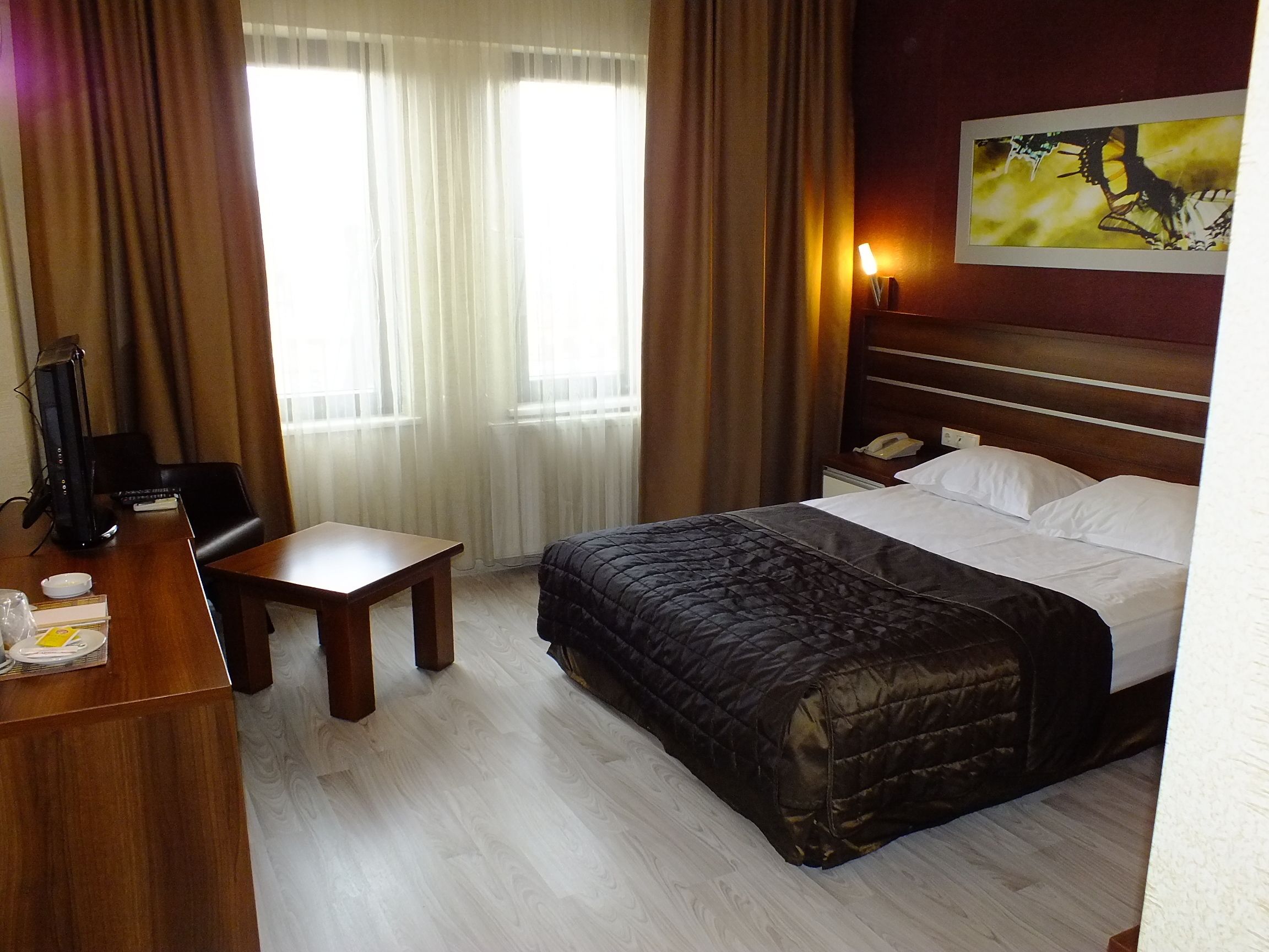 Habitación de hotel con cama, escritorio, silla y un cuadro en la pared.