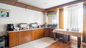 Una cocina moderna con estufa integrada, cafetera y comedor con mesa y sillas.