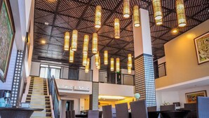 A spacious lobby with a high ceiling, multiple seating areas, and a staircase leading to upper floors.
