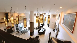A spacious lobby with high ceilings, hanging lantern-style lights, and artwork on the walls.