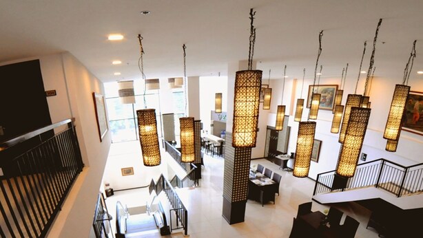 A spacious lobby with high ceilings, multiple seating areas, and hanging decorative light fixtures.