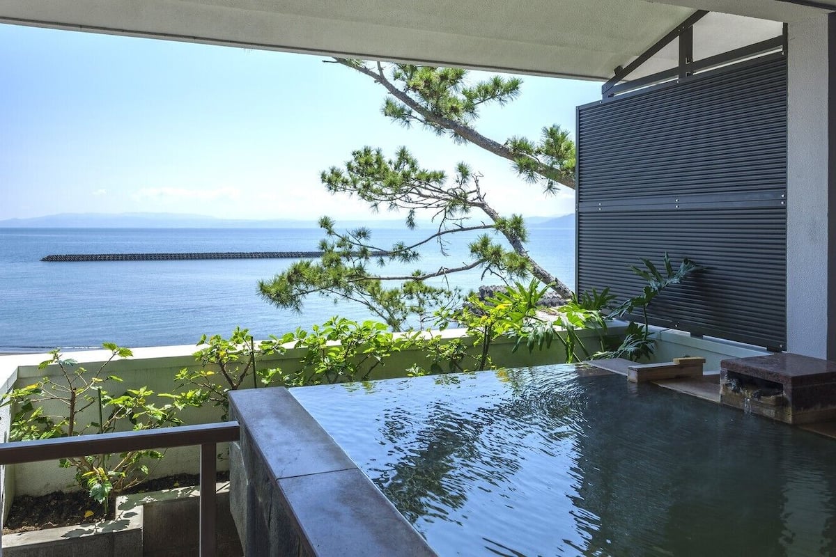 A balcony with a view of the sea, a pool, and a wooden deck.