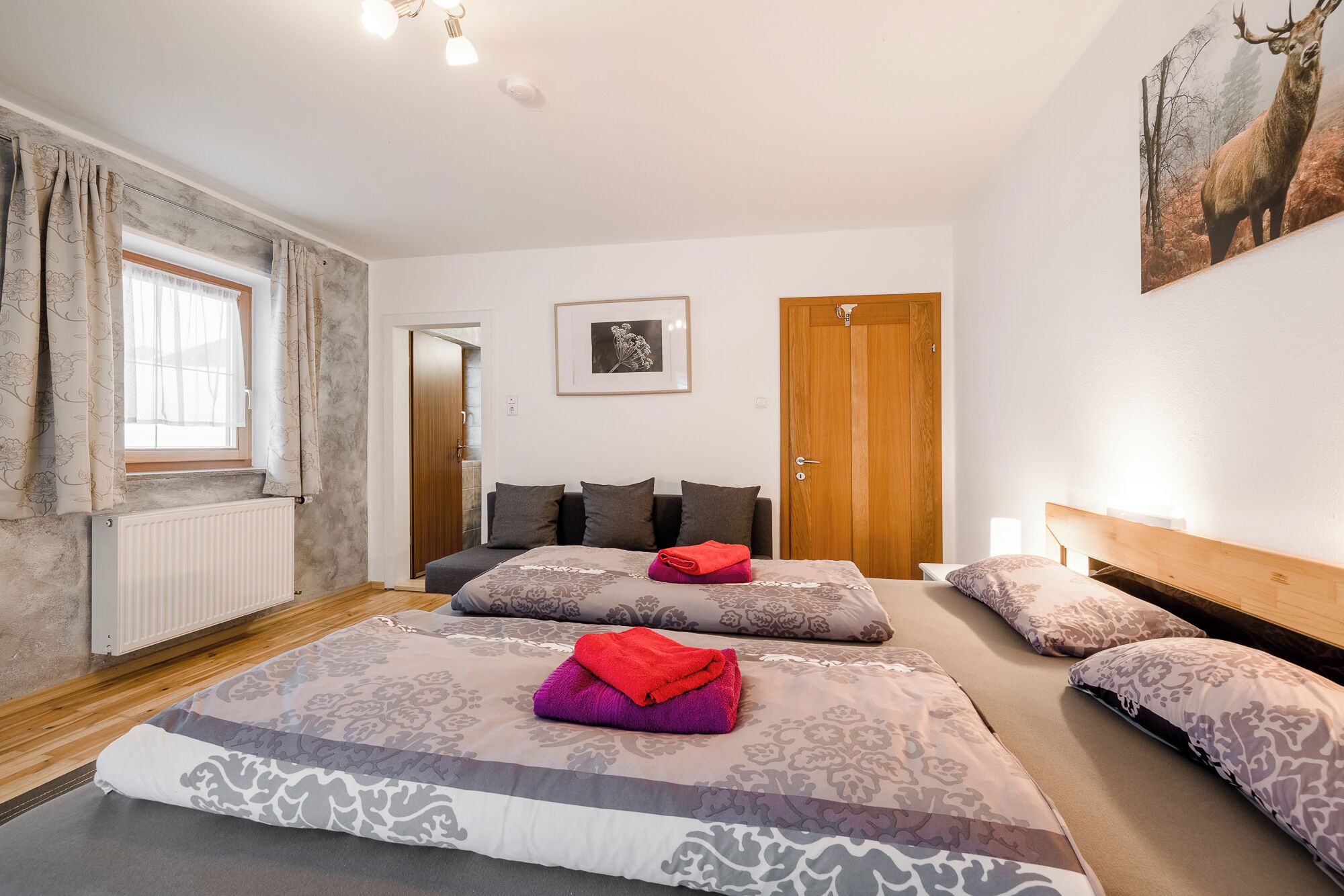 A bedroom with two beds, a radiator, a wooden door, and a framed picture on the wall.
