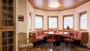 Een eethoek met een ronde tafel en een rode, beklede bank.