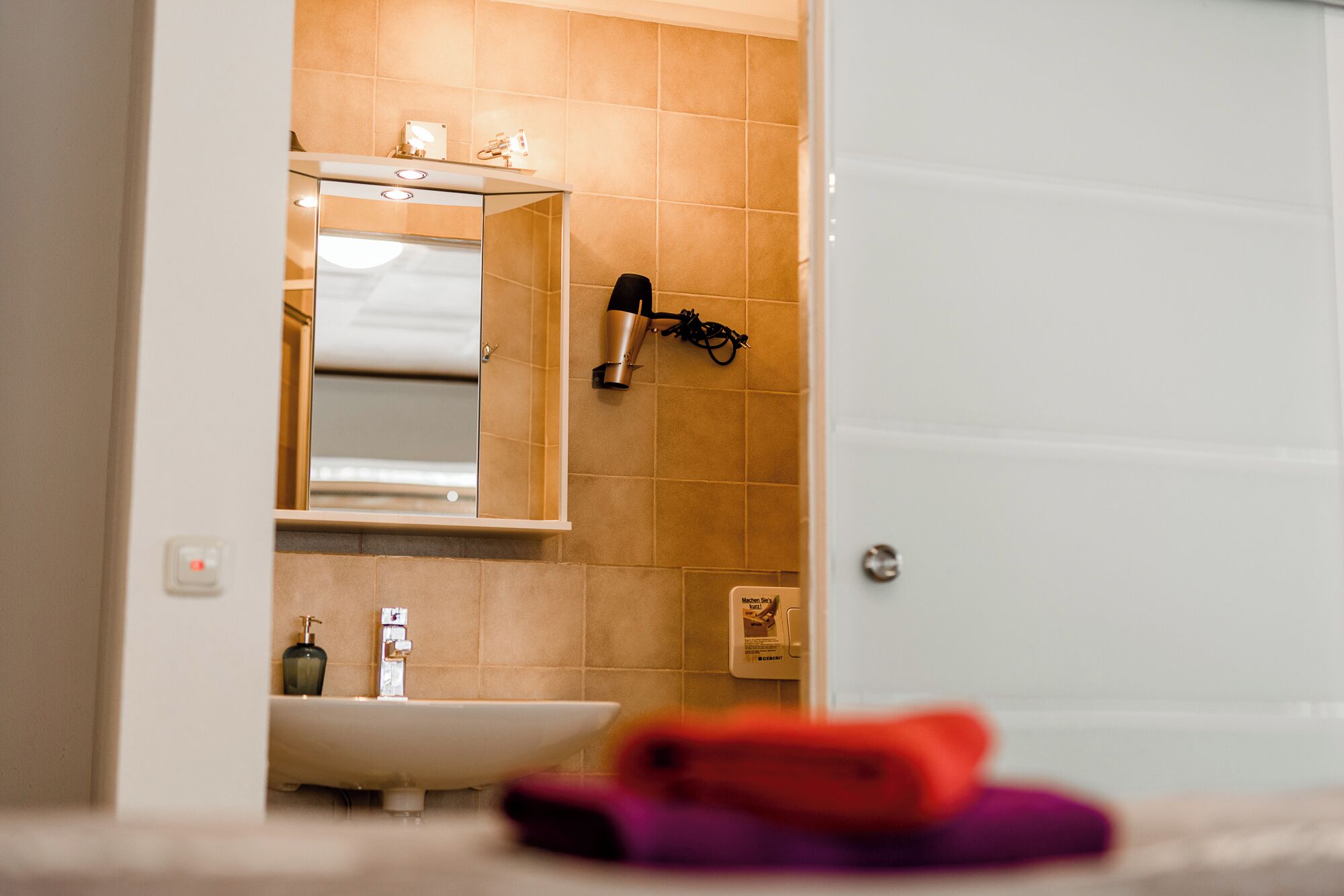Un bagno con lavandino, specchio e porta asciugamani.