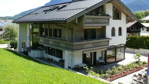 Een gebouw met twee verdiepingen, een balkon, een overdekte zithoek en een uitzicht op bergen.