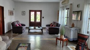 Uma sala de estar com dois sofás, uma mesa de centro e uma televisão na parede.