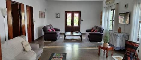 Una sala de estar con dos sofás, una mesa de centro y un televisor en la pared.