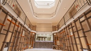 A spacious lobby with a central reception desk, a high ceiling with a skylight, and a modern design with wooden accents and metal railings. - Atrium Apart Hotel (Cesme)