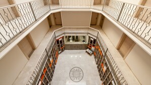 A multi-level interior with a central open space surrounded by balconies with metal railings. - Atrium Apart Hotel (Cesme)
