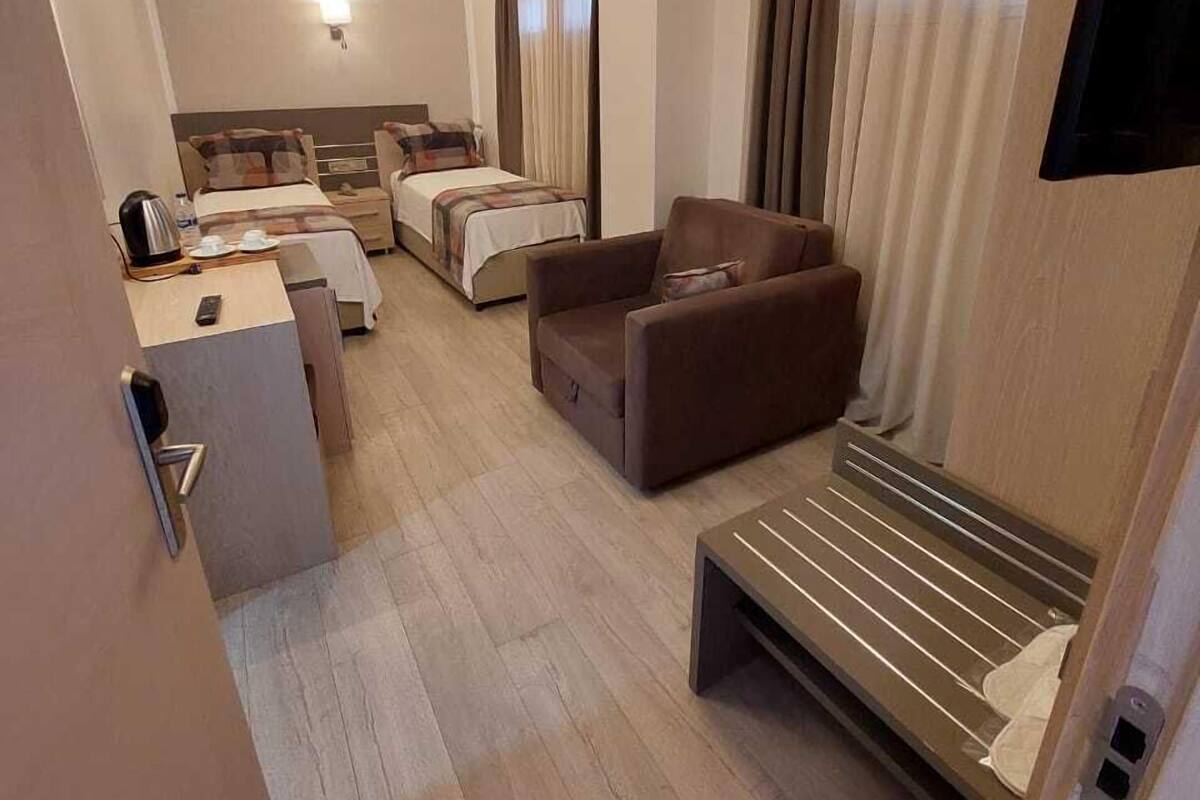A hotel room with a bed, a sofa, a desk, and a TV.