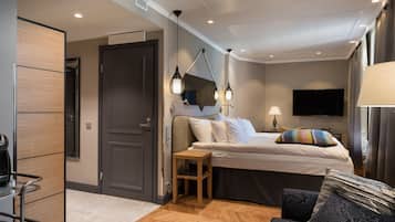 A modern hotel room with a bed, bedside table, lamp, and TV.