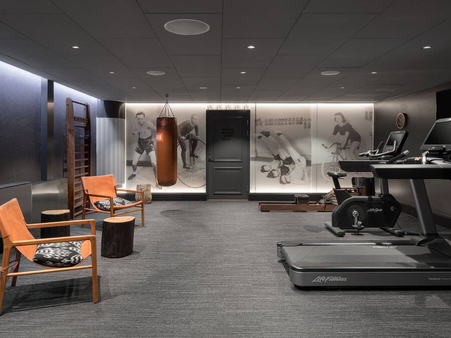 A fitness room with exercise equipment, including a treadmill and stationary bikes, and a punching bag.